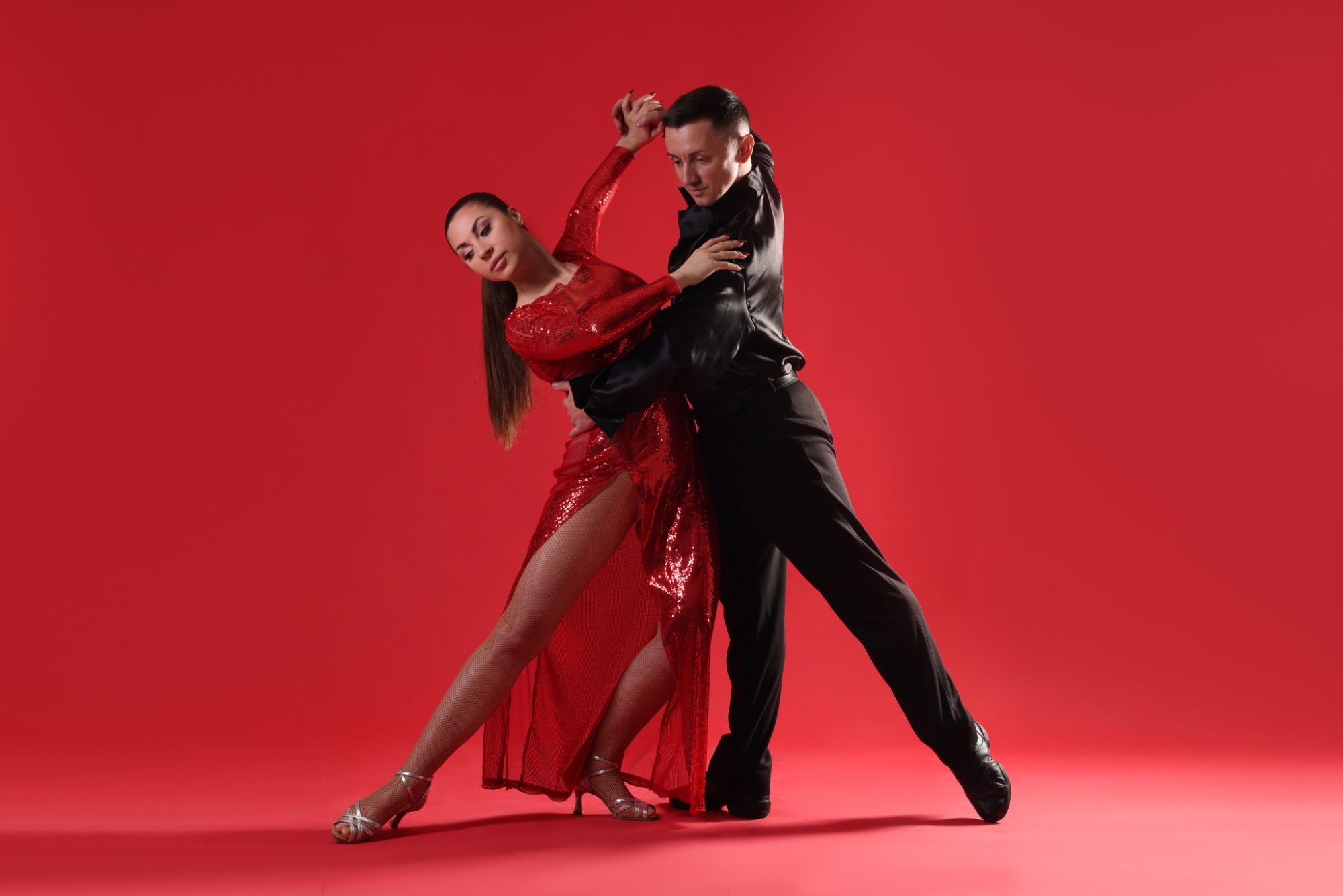 Dance couple in a salsa pose against a red background