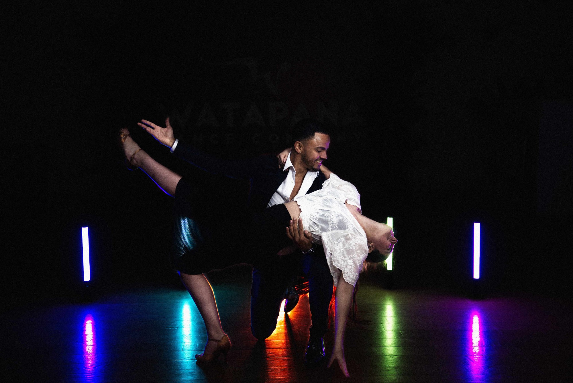 Watapana dance couple in a dip in front of the Watapana logo